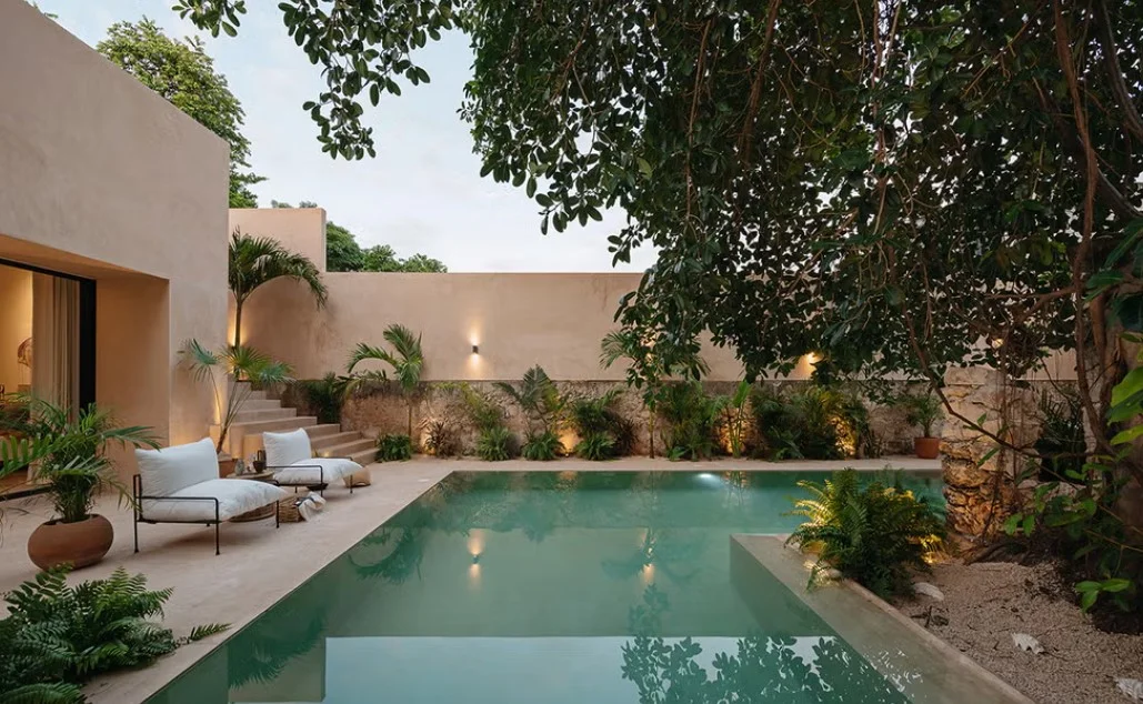 Garden swimming pool framed by trees and sun loungers